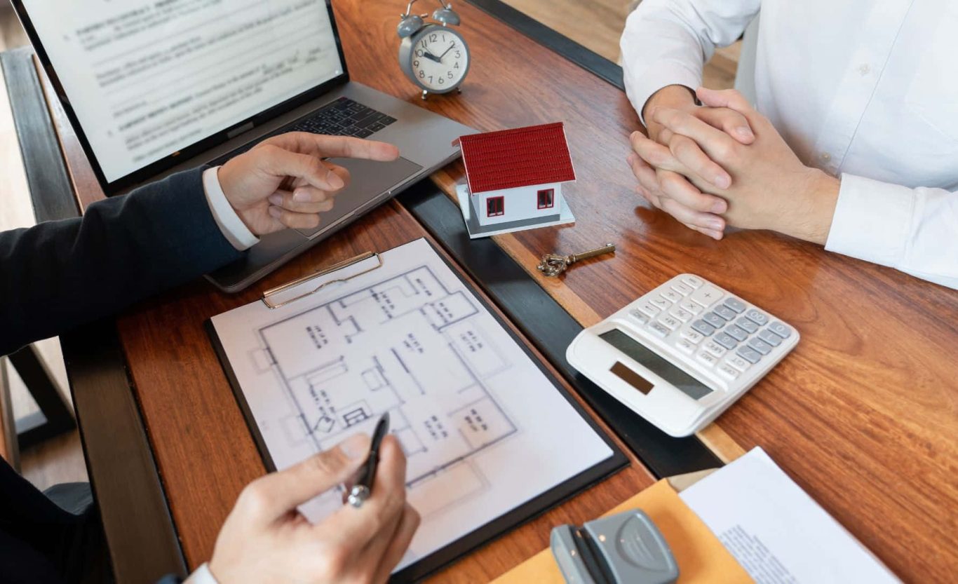 Sachverständiger bewertet Immobilie anhand von Unterlagen und Hausmodell – professionelle Immobilienbewertung in Ostwestfalen‑Lippe.